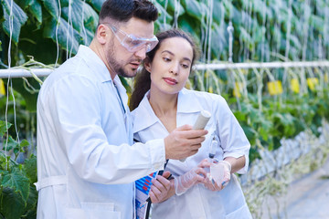Waist up portrait of two modern scientists checking quality of production taking probes in...