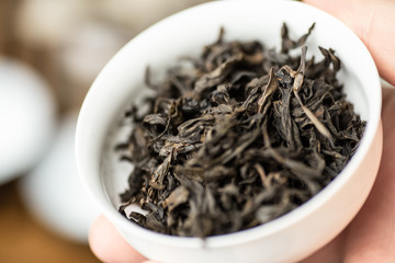 Da hong pao oolong tea in gaiwan or tea-cup in human hand, macro shot with selective focus, Chinese tea ceremony