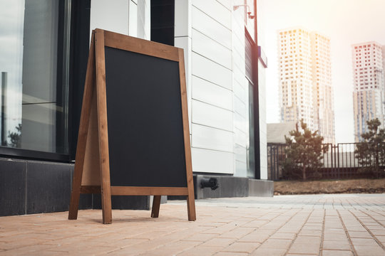 Blank Sandwich Board at the Street Near Cafe Or Pub. Business Center, Commercial Center, Downtown.  Copy Space, Empty Space for Advertising