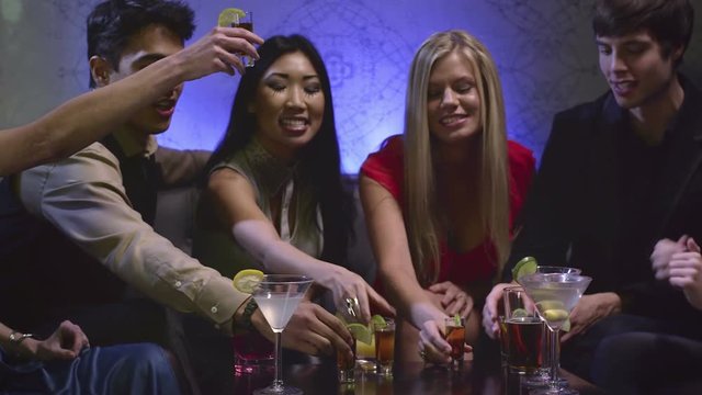 Group of friends sitting at a table in a club cheering there drinks