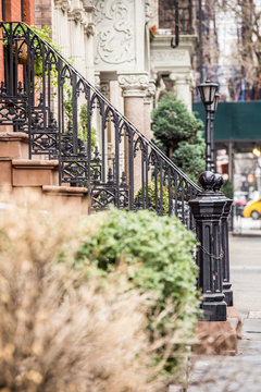 Vintage looking New York City Manhattan street scene from sidewalk with pretty apartment building with railing and lamp post.