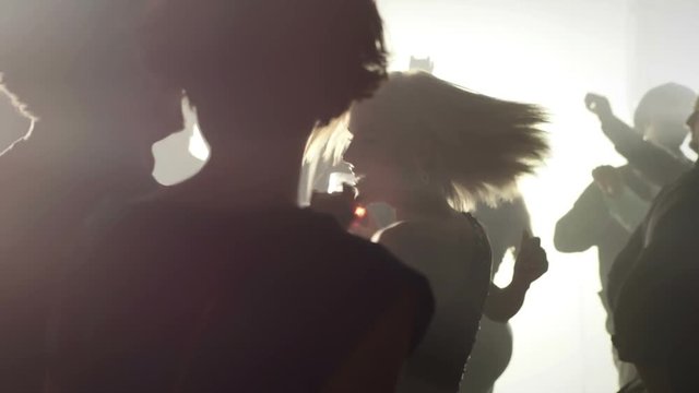 Silhouette in a smokey room of a group of people dancing while at a club