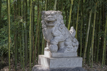 Fototapeta na wymiar Statue of Chinese guardian lion in a bamboo forest