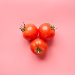 Ripe tomato on pink background. Creative concept. Square format. Top view.