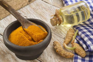 Ground turmeric in a bowl on wooden background- turmeric longa
