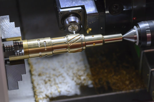 The CNC turning or lathe machine cutting groove slot at the brass shaft by the milling spindle. High technology manufacturing process.