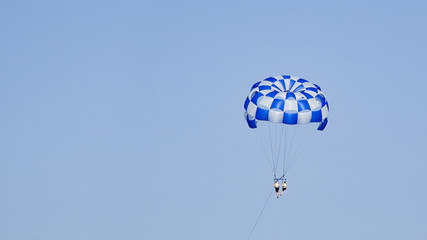 Two people on sea parasail parachute flight with blue sky copyspace