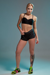 Fitness woman in black tank top and shorts, studio shot.