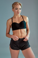 Fototapeta na wymiar Fitness woman in black tank top and shorts, studio shot.