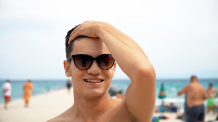 summer holidays and people concept - happy smiling handsome young man in sunglasses on beach