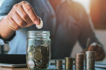 businesswoman saving money by hand puting coins in jug glass. concept  finance and accounting