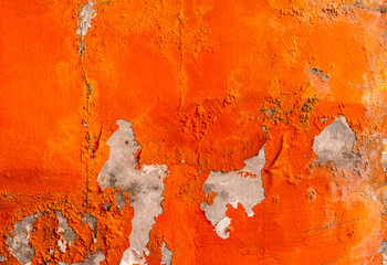 Orange color painted on concrete wall are peeling. Old and dirty wall texture background with space.