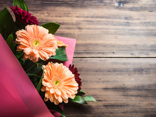 Gentle flowers on wooden background, top view. Bouquet for congratulations, wedding flowers closeup. Decoration made of chrysanthemums, daisies, green plants for birthday card. Selective soft focus