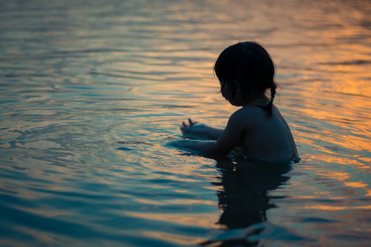 Poor Baby Girl Playing Water On Sunset