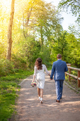 Fototapeta na wymiar Brautpaar geht Weg entlang und hält die Hände und Brautstrauß