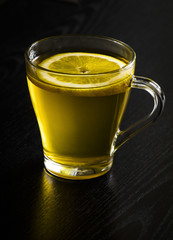 Lemon slice in fresh tea on a black background close-up.