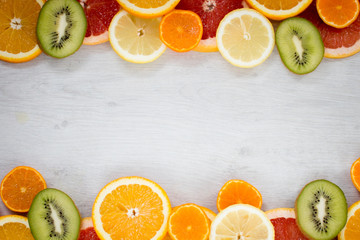 Sliced juicy orange, lemon, kiwi, grapefruit and mandarin on the wood background