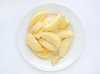 Peeled and sliced apples on white plate. top view.