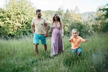 Fototapeta premium A family going on a walk in the nature. A man and a woman holding hands and walking after their little son.