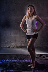 Fototapeta premium Portrain of the girl in the white shirt with water drop in a dark room illuminated by light during a photoshoot with water