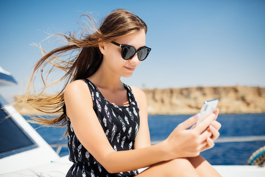 Young woman travel with smartphone on yacht. Chatting on smartphone on yacht.