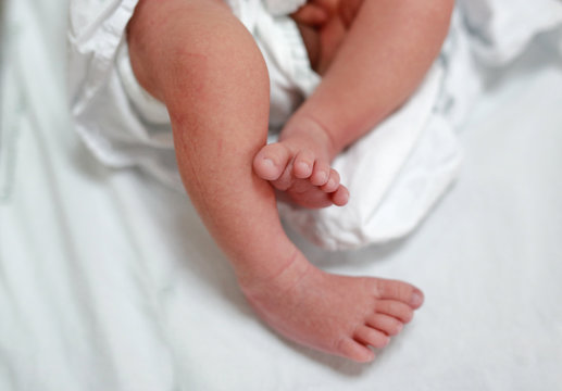 Close up little baby feet under the sheet.