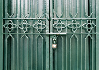 Wrought iron door green color locked with a padlock. vintage grungy style closing the door background.