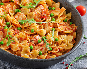 Farfalle pasta with chicken fillet, tomato sauce and green peas. Tasty food. Italian meal