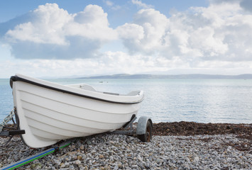 Small white dinghy on a trailer close to the sea