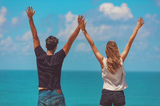 Couple with arms wide open enjoying the ocean / sea view.