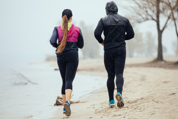 Two friends jogging by the river, rear view