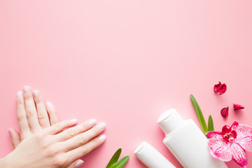 Beautiful, groomed woman's hands. Moisturizing cream bottles for clean, perfect and soft skin. Beauty concept. Mock up for special offers. Copy space. Empty place for text or logo on pink background.