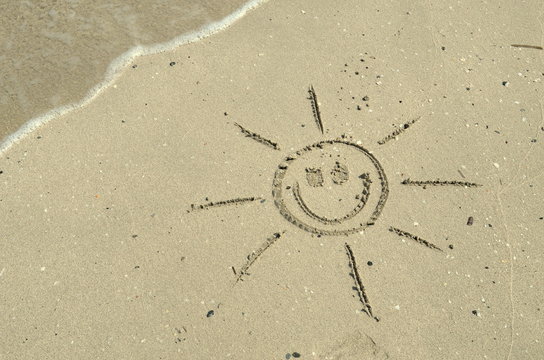 Sun drawn in sand on beach