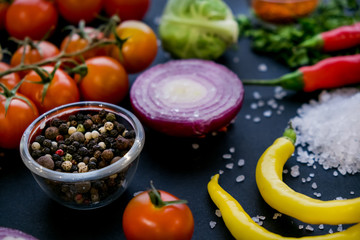Close up of colorful spices and fresh vegetables for cooking on dark metal background with space for text. Top view. Bio Healthy food ingredients.