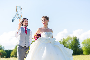 Happy wedding groom catching bride with net