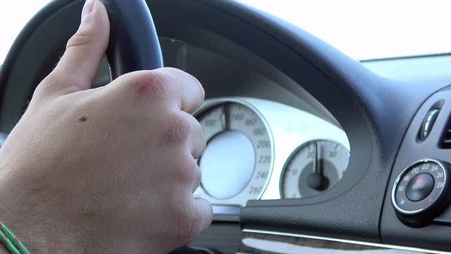4K. Driving a car on a freeway, Close up of the hand on the steering wheel, at the back is the car's speedometer-Adrian.