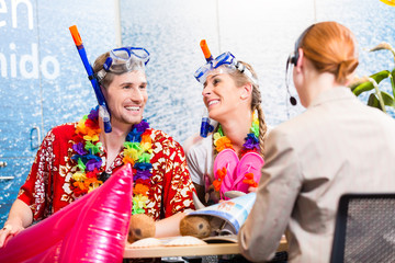 Man and woman booking beach holiday in travel agency wearing their vacation outfit 