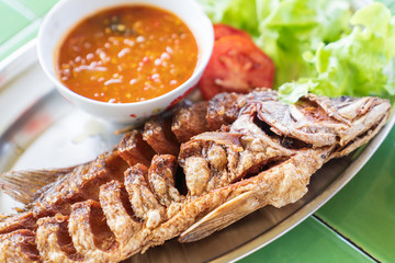 Fried fresh big fish with salad and hot spicy sauce.