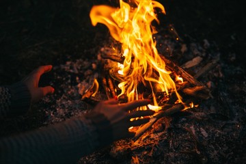 Traveler warming his hands by the campfire in forest.Survival travel,lifestyle concept.