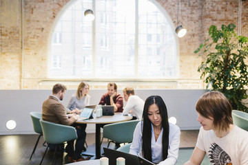 Group of young students with their laptops in canteen