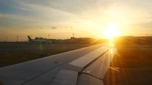 Travel Video View of airplane wing. Plane on the runway are preparing for take off at international airport with sunset in travel and transportation concept.