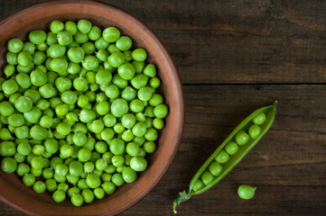 Green peas in a bowl on a wooden background