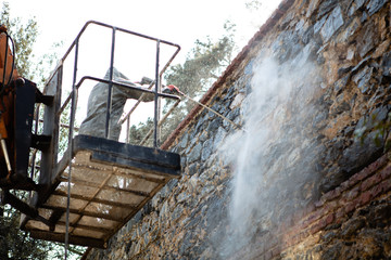 Outdoor worker cleaning the exterior wall of building