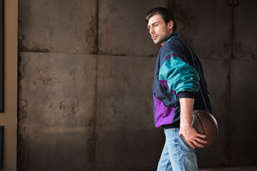 serious young man in vintage windcheater with basketball ball