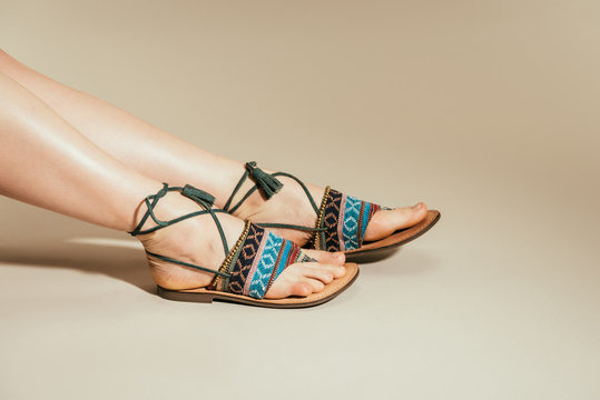 Cropped Image Of Woman Feet In Stylish Sandals On Beige Background