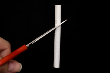 Quit smoking. Closeup of female hands of cigarette and cutting  in halves with scissors on a black background. Stop smoking cigarette concept