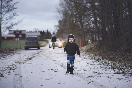 Small boy walking on road in winter