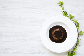Panacotta dessert with chocolate in white plate on white wooden background decorated with...