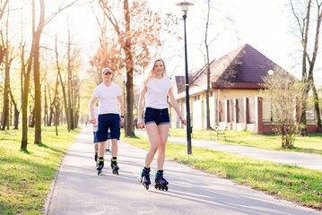 Couple roller skating on the park road.