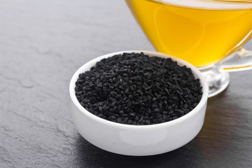 grains of black cumin and oil on the rustic background